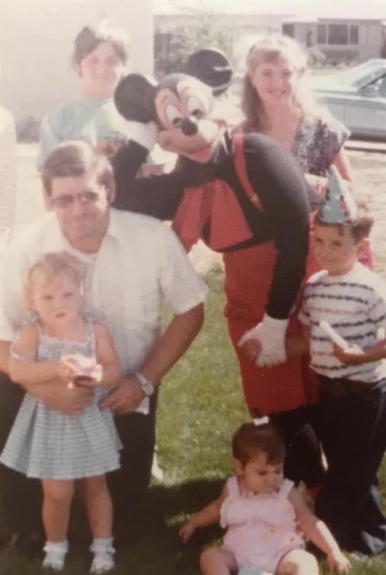 A joyful family is gathered outside, enjoying a celebration with a costumed character.