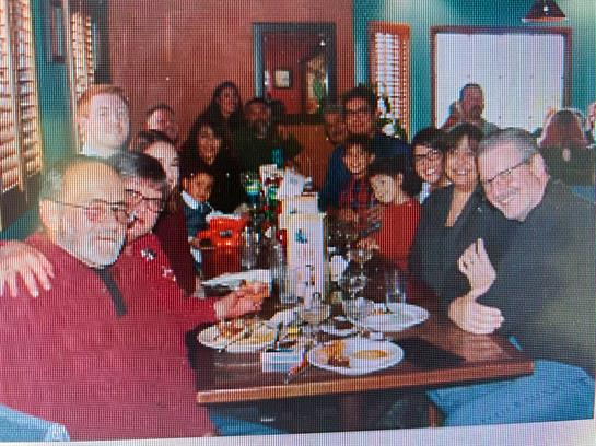 A lively gathering of family and friends sharing a meal in a cozy restaurant setting.