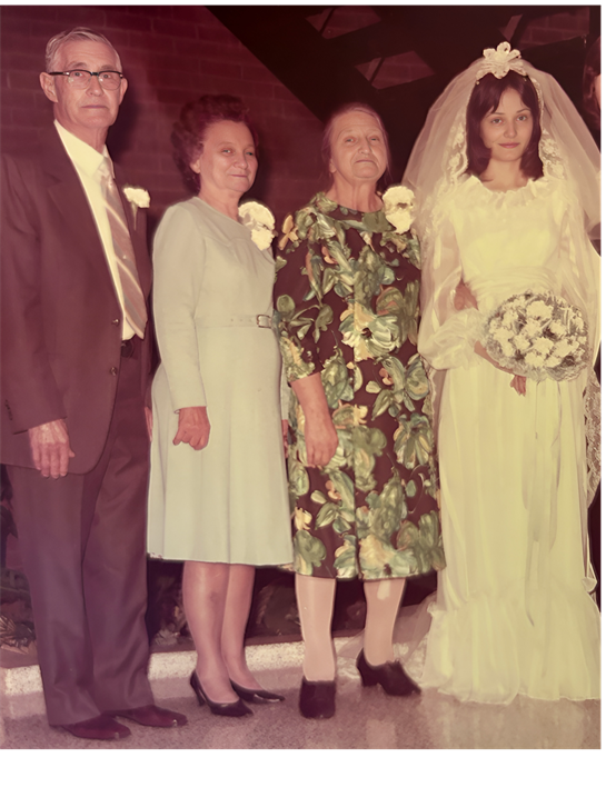 A joyful family stands together, celebrating a wedding with formal attire and floral arrangements.
