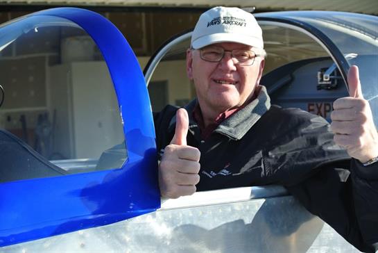 A man in a cap and glasses holding his thumb up