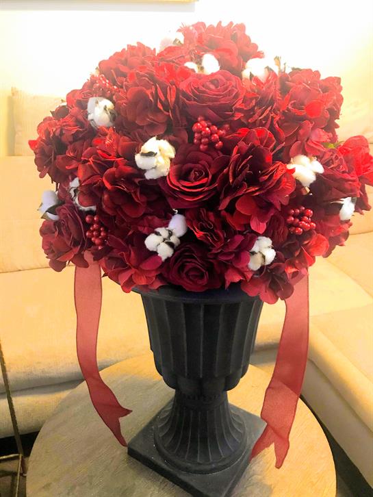 A lovely mix of red flowers and cotton adorns the table, enhancing the room's decor.
