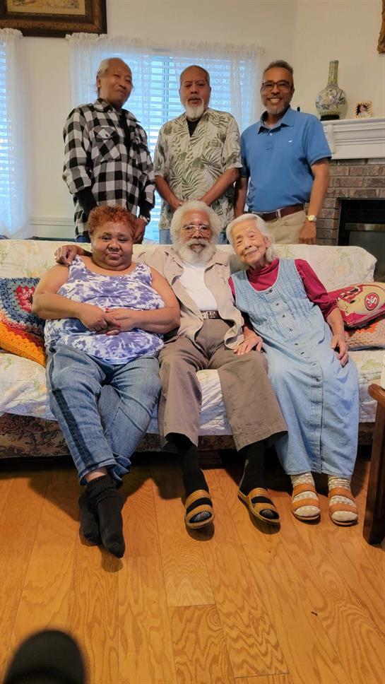 A group of seniors and family members smile happily while sitting closely on a comfortable sofa.
