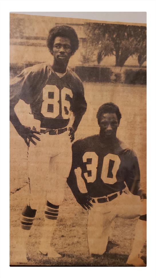 Two football players stand proudly in their jerseys, showcasing their team spirit and camaraderie.