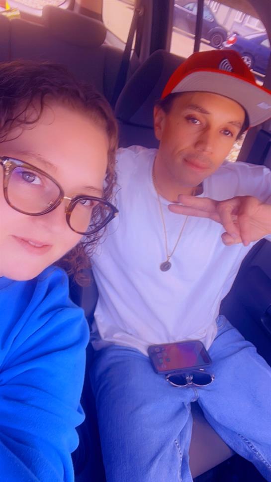 Two friends relax in a vehicle, sharing smiles and showing peace signs while enjoying their time.