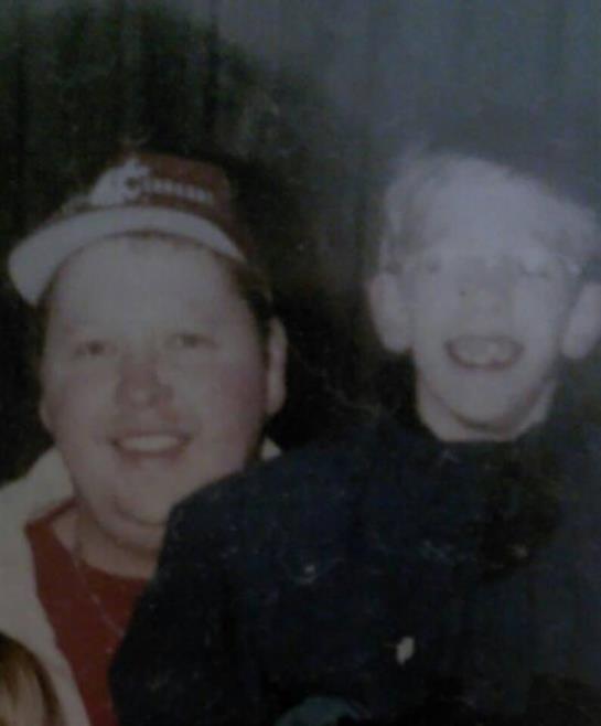 Two smiling individuals, one adult and one child, share a joyful moment at a celebration indoors.