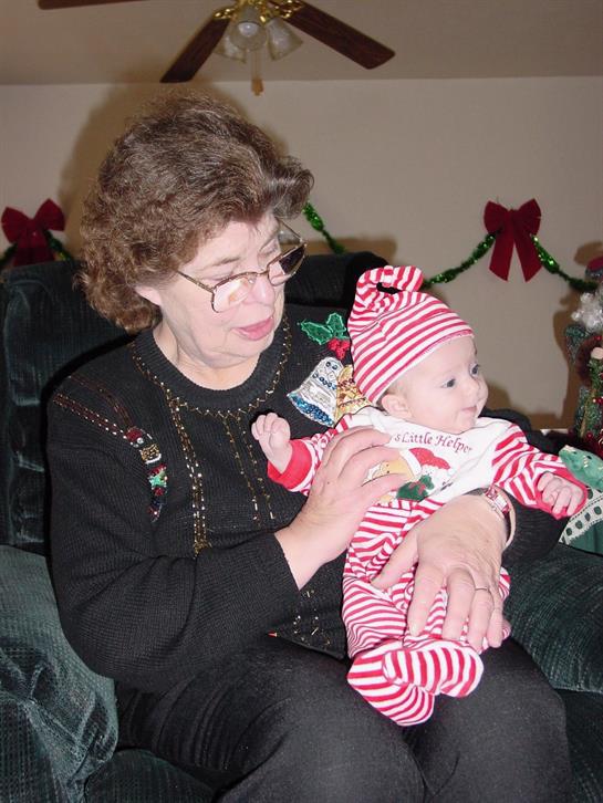 Grandmother lovingly interacts with a baby dressed in festive clothing during a family celebration.