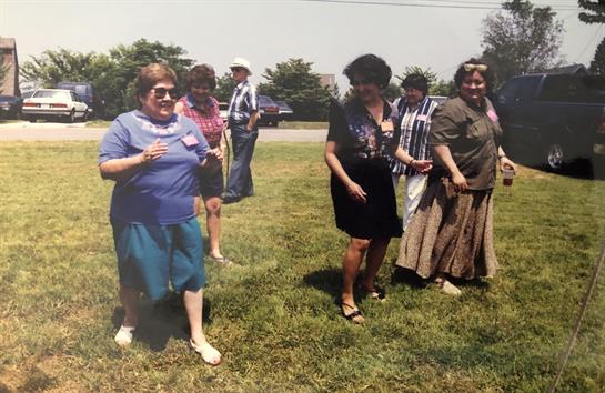 People are dancing together in a sunny outdoor setting, enjoying a social event during summer.