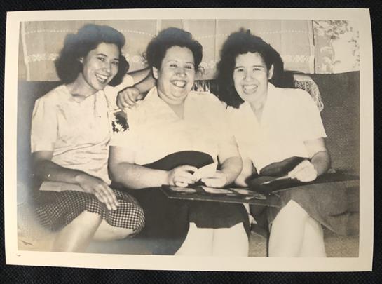 Three women share laughter and good times while relaxing in a cozy indoor space.