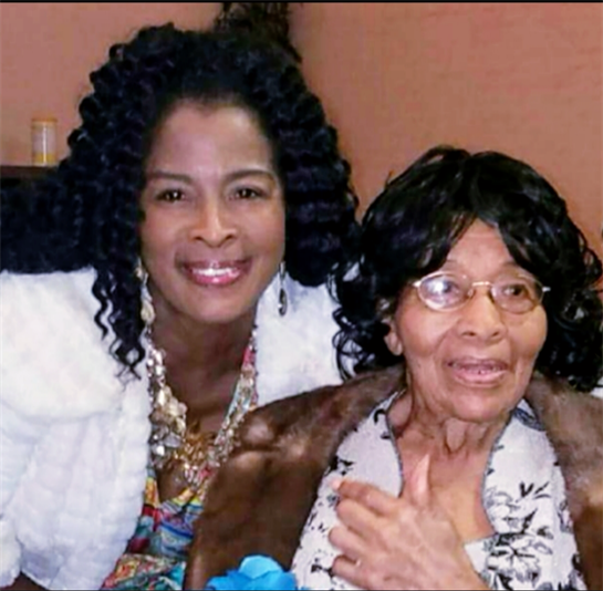 A younger woman smiles brightly beside an older woman enjoying a treasured family event together.