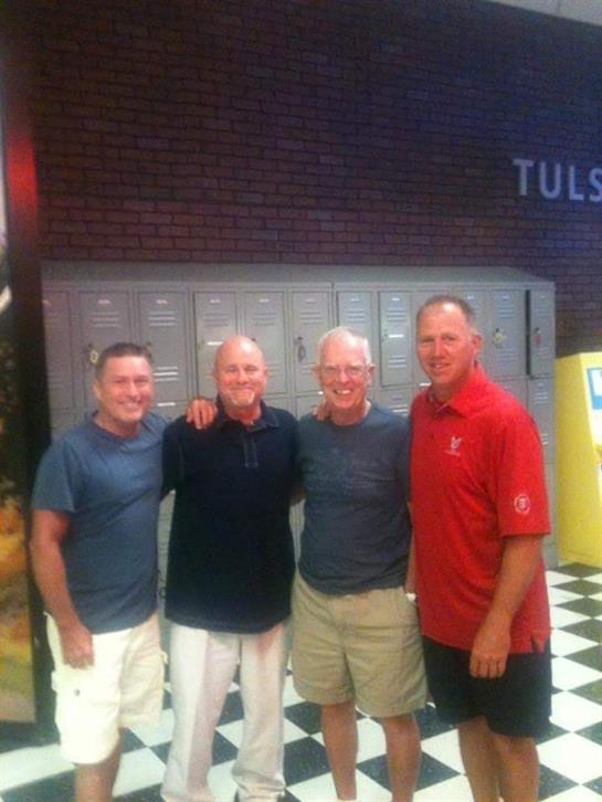 Four friends enjoy a casual reunion, sharing stories and smiles in a Tulsa venue.