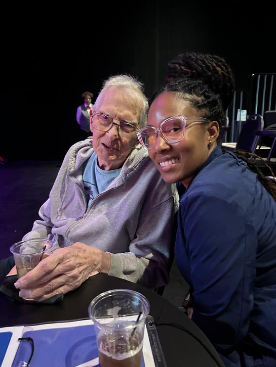 An elderly man and a young woman share a joyful moment, attending a lively event together.