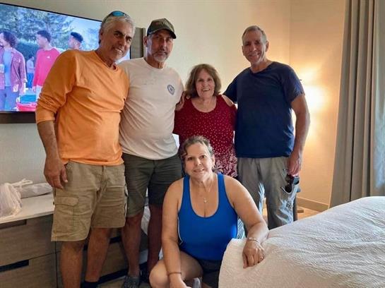 Five friends gather in a hotel room, smiling and celebrating their vacation memories.