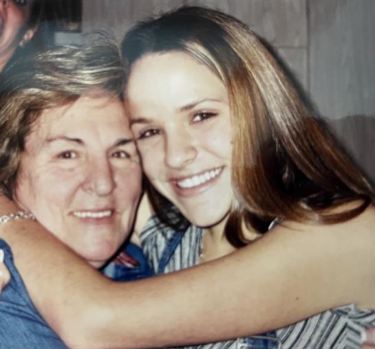 A grandmother and granddaughter share a joyful hug, showcasing their close bond and happiness.