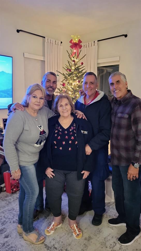 A group of five family members enjoys a cheerful moment together by a decorated Christmas tree.