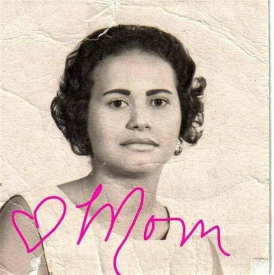 A woman with curled hair poses in an elegant dress, signed 'Mom,' sparking nostalgia.