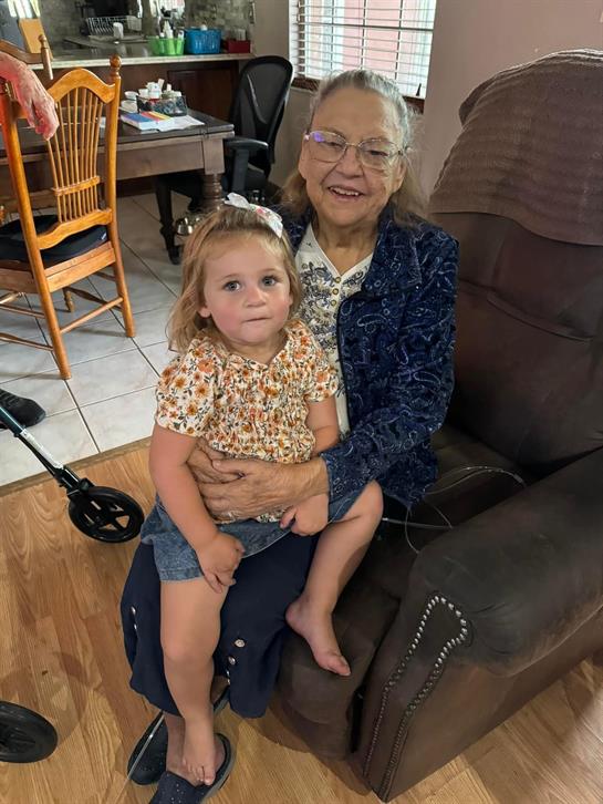 Grandmother sits comfortably with her granddaughter on her lap, creating a heartwarming moment.