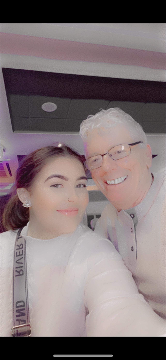 Two individuals share a joyful moment, smiling for the camera at a vibrant social event.