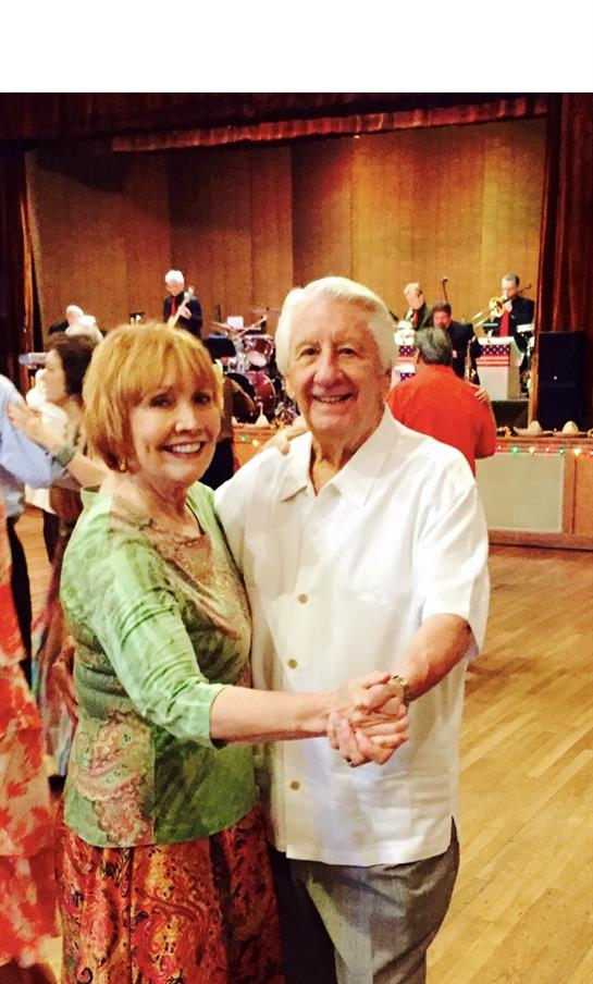 Elderly couple dances joyfully together while a live band performs in the background.