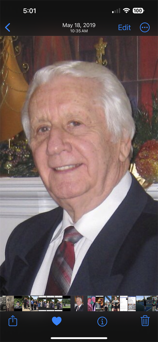 A man in formal attire shares a joyful smile at a festive gathering surrounded by decorations.