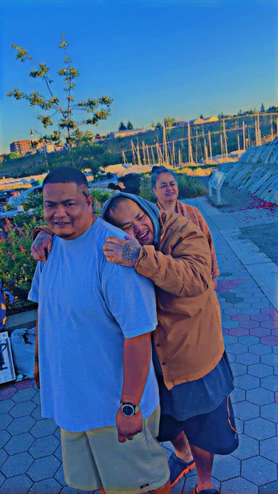 Group of friends smiling together by the waterfront at sunset, enjoying each other's company.