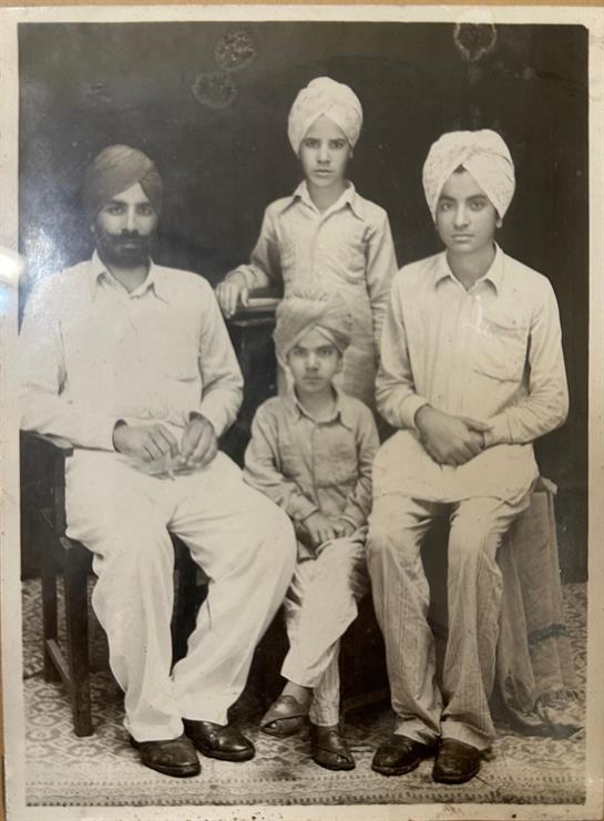 Four individuals in traditional attire pose together in a studio setting, showing family bond.