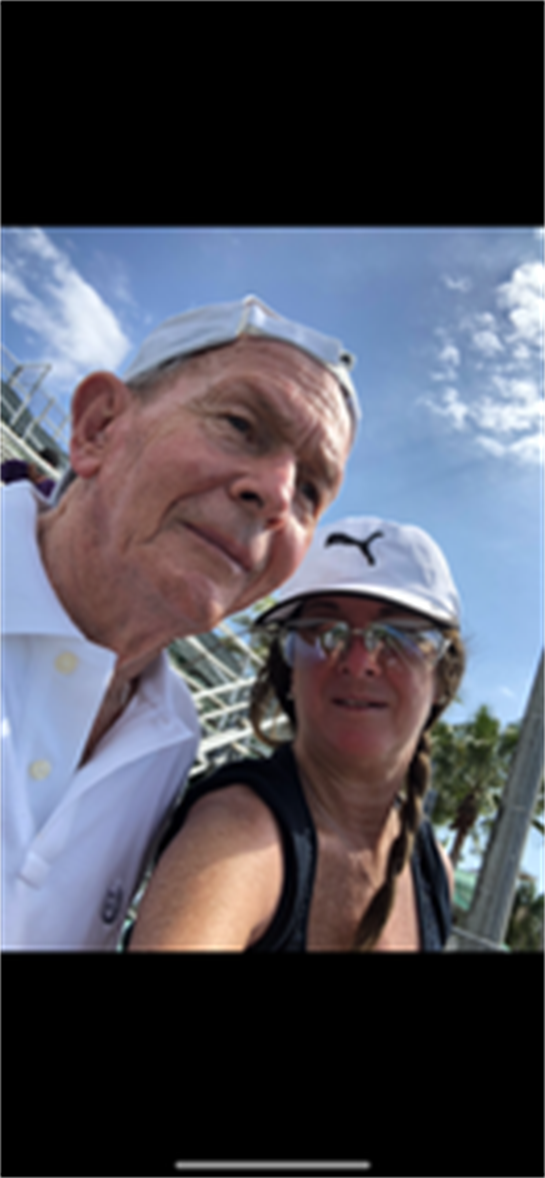 A senior couple smiles together under a clear sky by the beach, enjoying their time outdoors.