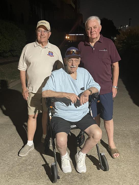 Three elderly men connect with each other during a calm evening walk in their neighborhood.