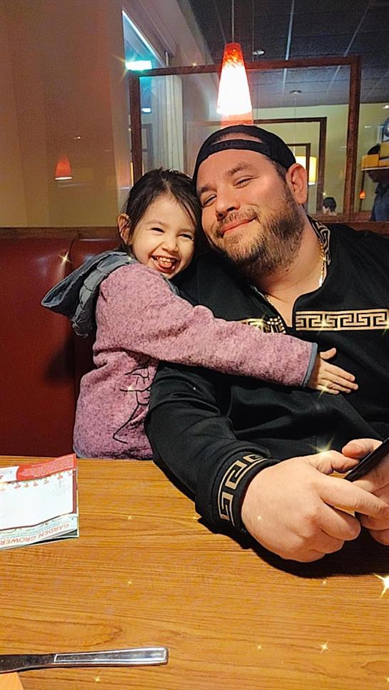 A child joyfully hugs an adult as they share a meal in a cozy restaurant.