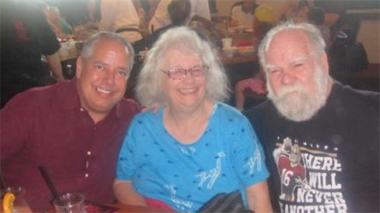 Three friends share laughter and conversation while dining at a bustling restaurant.