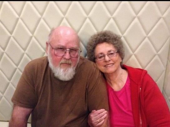 A happy couple smiles while sitting close together in a comfortable atmosphere.