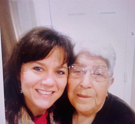 Two women share a joyful moment, smiling warmly together in a home setting.