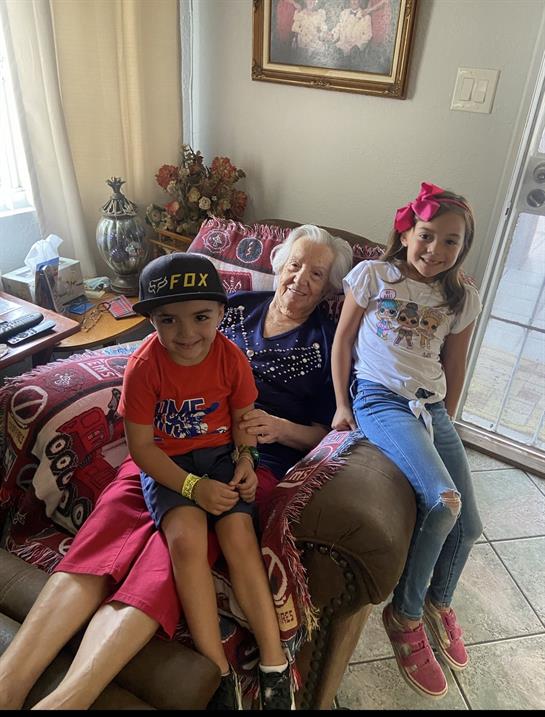Two children enjoy time with their grandmother in a cozy living room, sharing smiles and laughter.