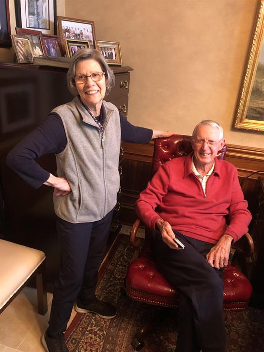 Two smiling individuals share a joyful moment while sitting in a comfortable living room.