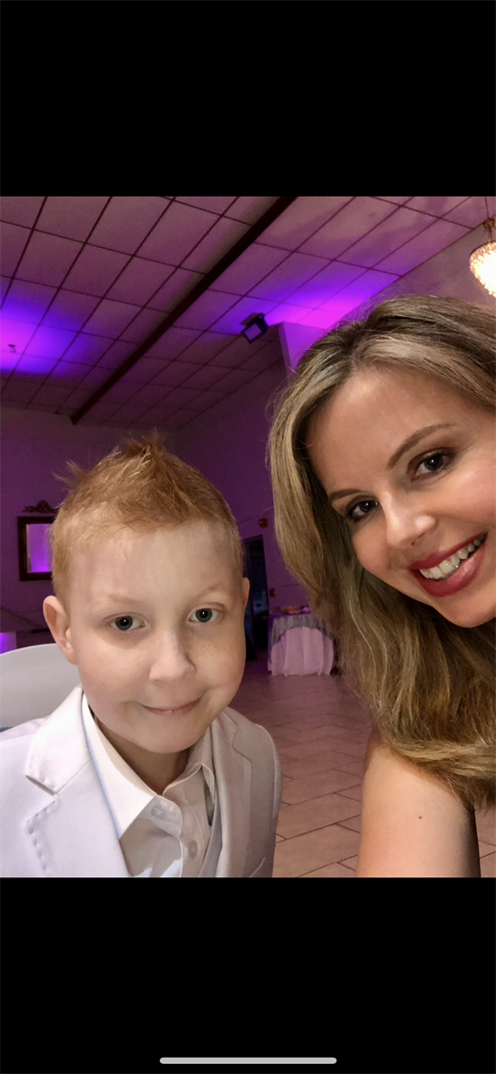 A young boy with a spiky haircut and a woman with long hair enjoy a joyful moment together.