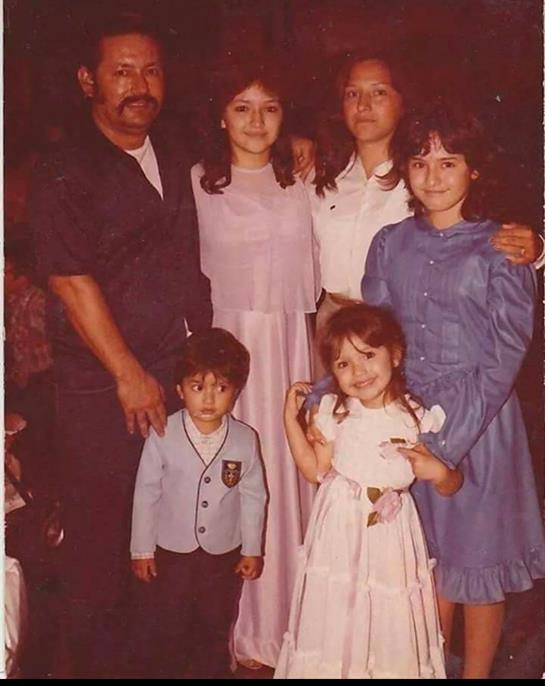 A family smiles together in vibrant clothing, capturing a joyful moment.