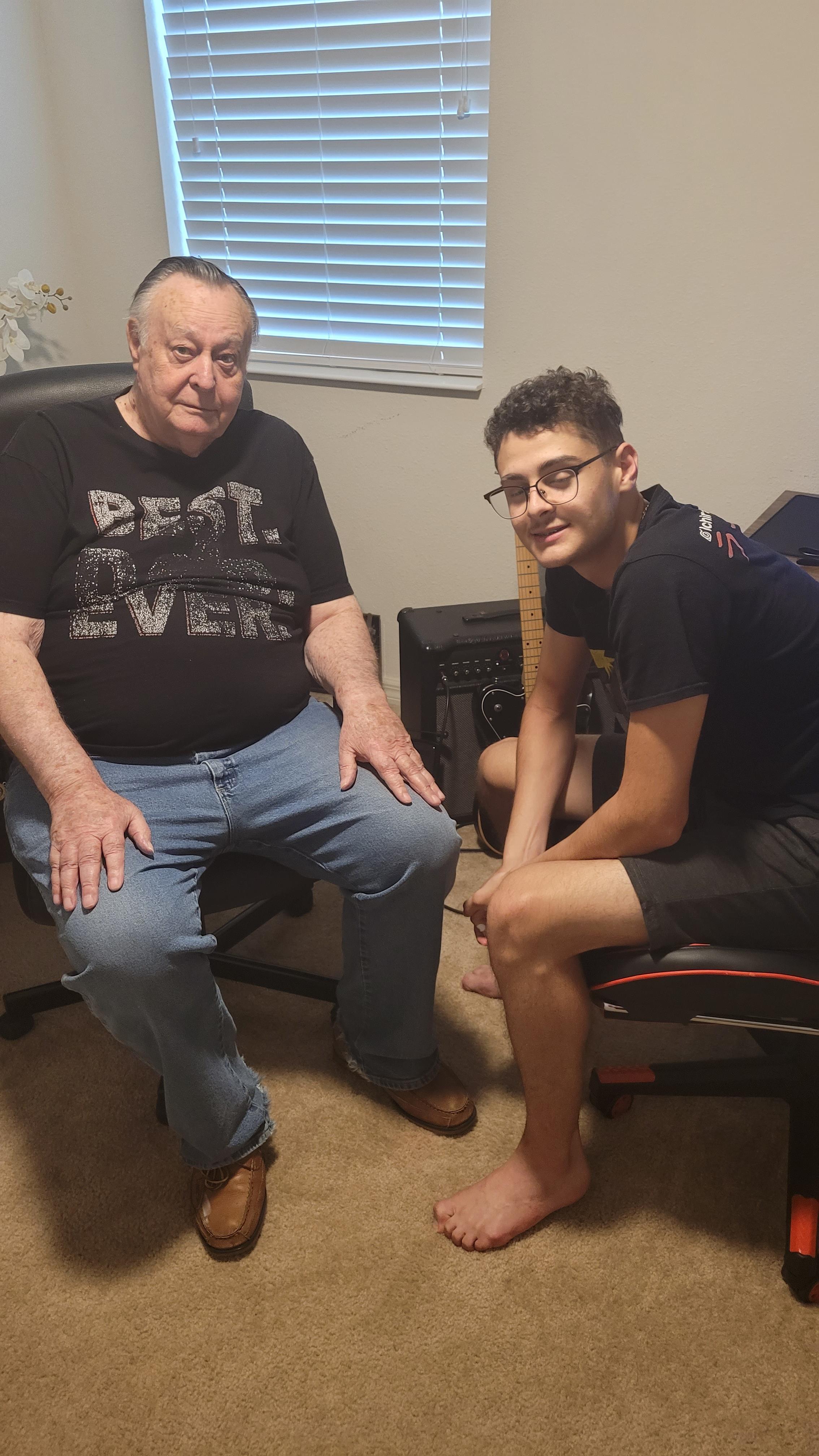 An older man and a young man sit together in a cozy room, sharing a moment of connection.