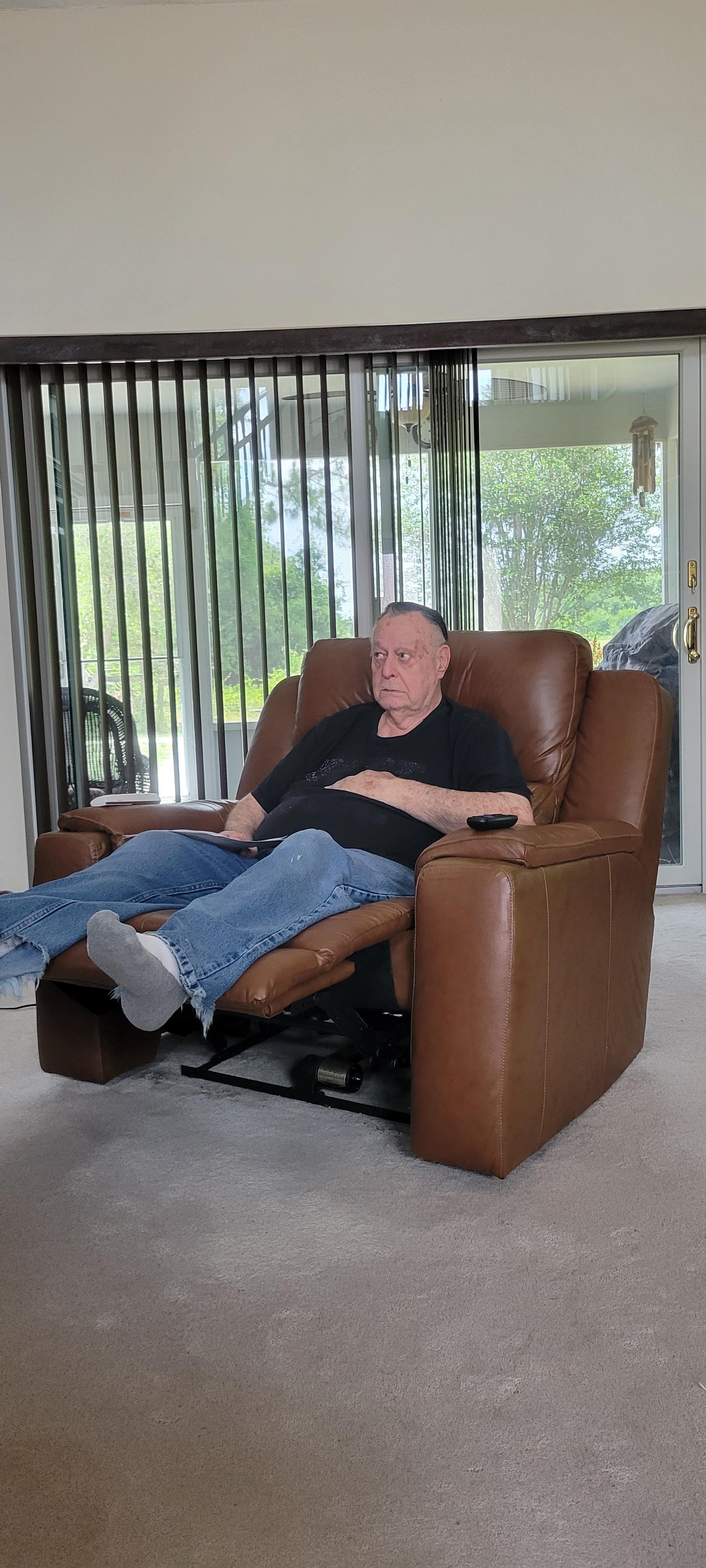 An elderly man sits comfortably in a recliner, enjoying a quiet moment in his cozy living room.