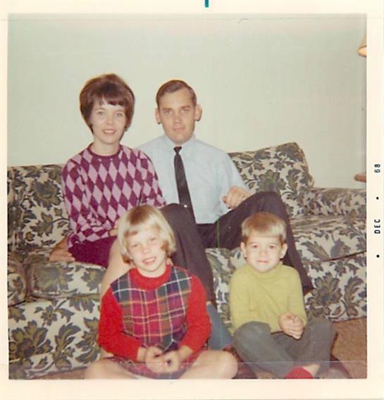 Four family members pose together on a patterned couch, showcasing smiles and warmth in their home.