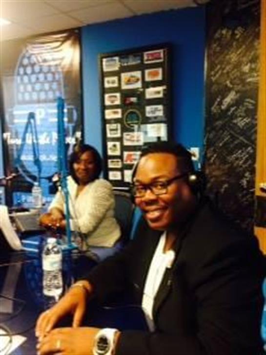 Two people share insights in a radio studio with blue walls and broadcasting equipment.