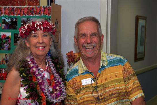 Cheerful couple wearing leis and colorful clothing enjoys a community celebration.