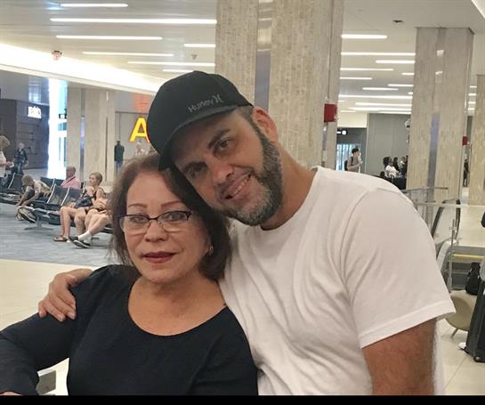 Two family members enjoy a warm embrace while seated at the airport lounge before a flight.