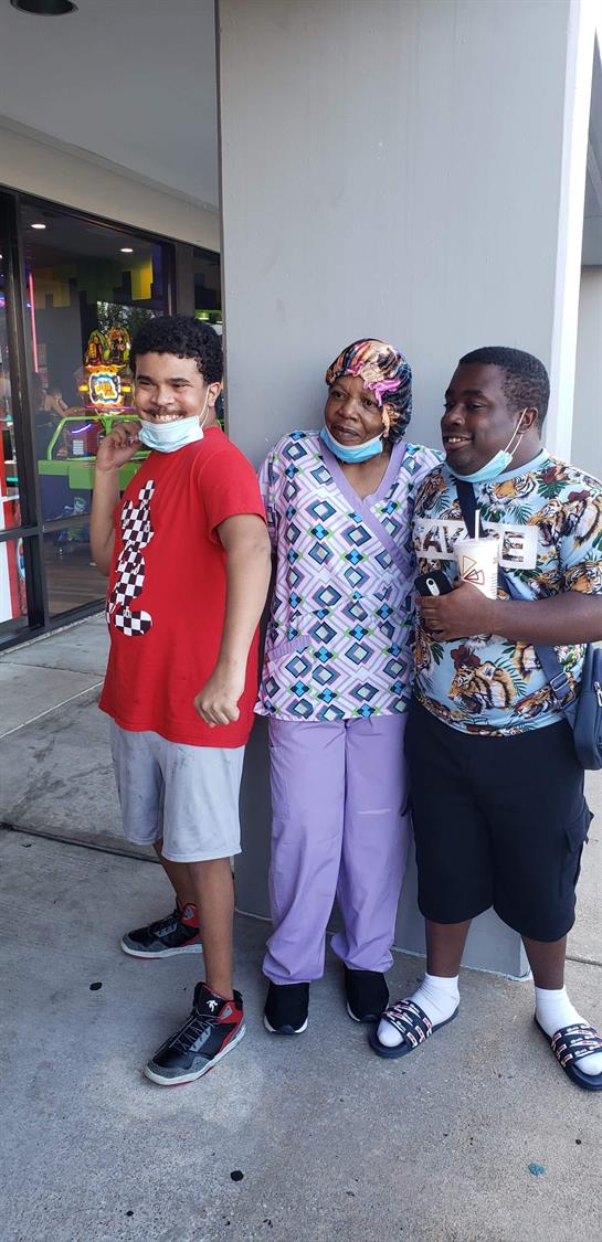 Three individuals pose together outside a store, all wearing masks and enjoying their time.