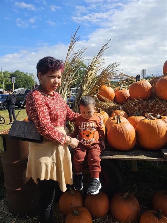 A woman and a child sitting on a table with pumpkins