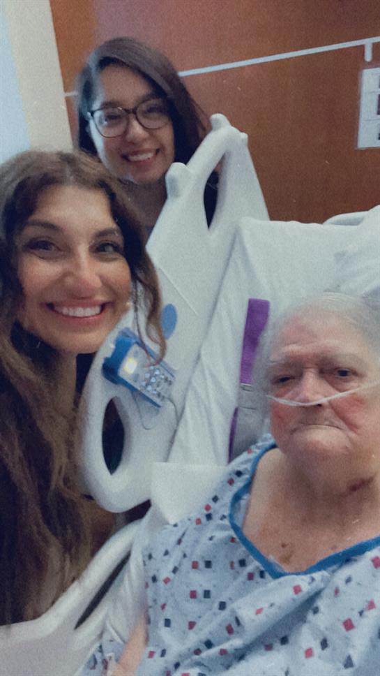 Two relatives share a heartfelt moment with their grandmother in a hospital room.
