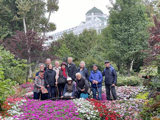 Visitors gather in a vibrant garden filled with blooming flowers and greenery in autumn.