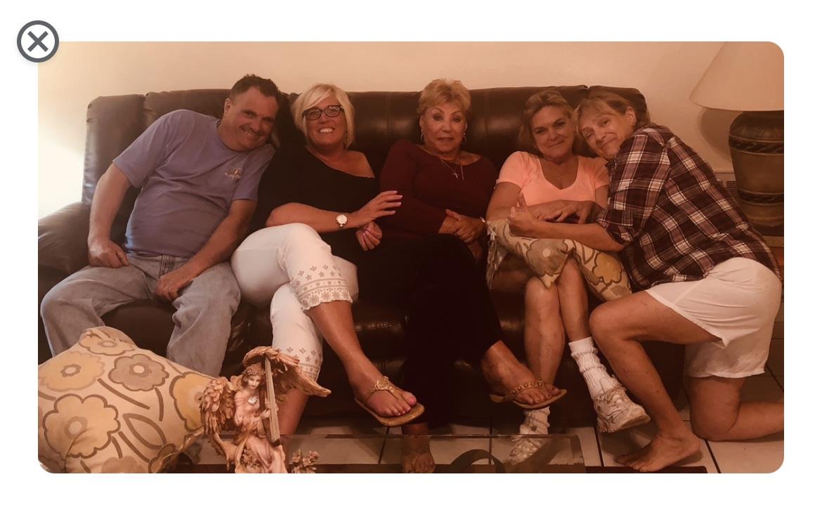Five family members enjoy a relaxed gathering while seated on a comfortable couch at home.