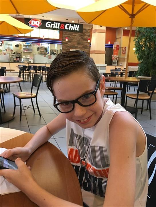 A boy sitting at a table with glasses