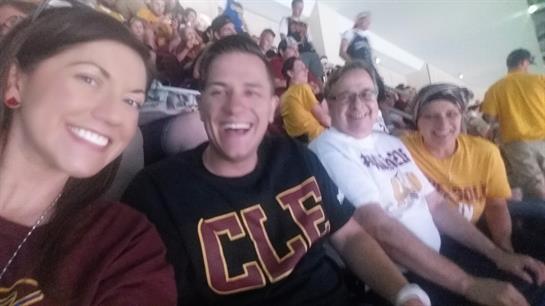 Group of friends smiling and posing together at a sports event in a bustling arena.