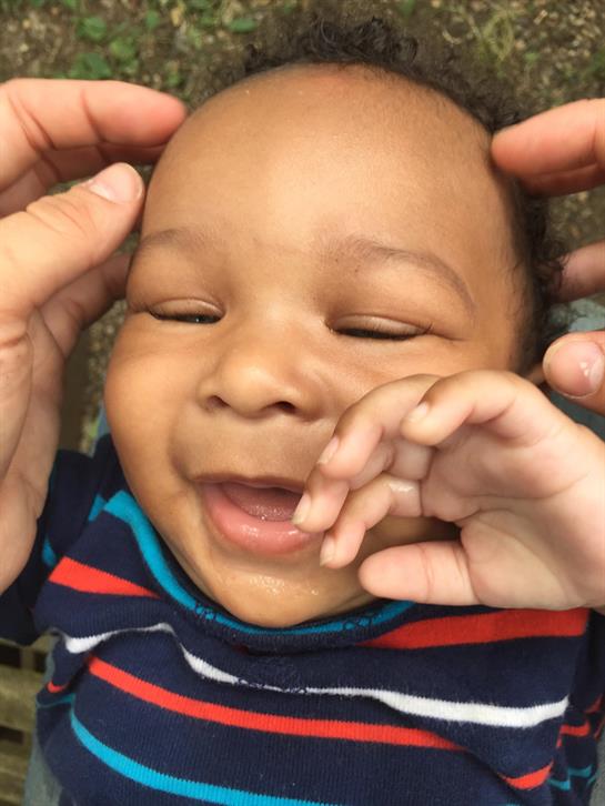 Happy baby enjoys playful interaction, smiling brightly in a nurturing environment.