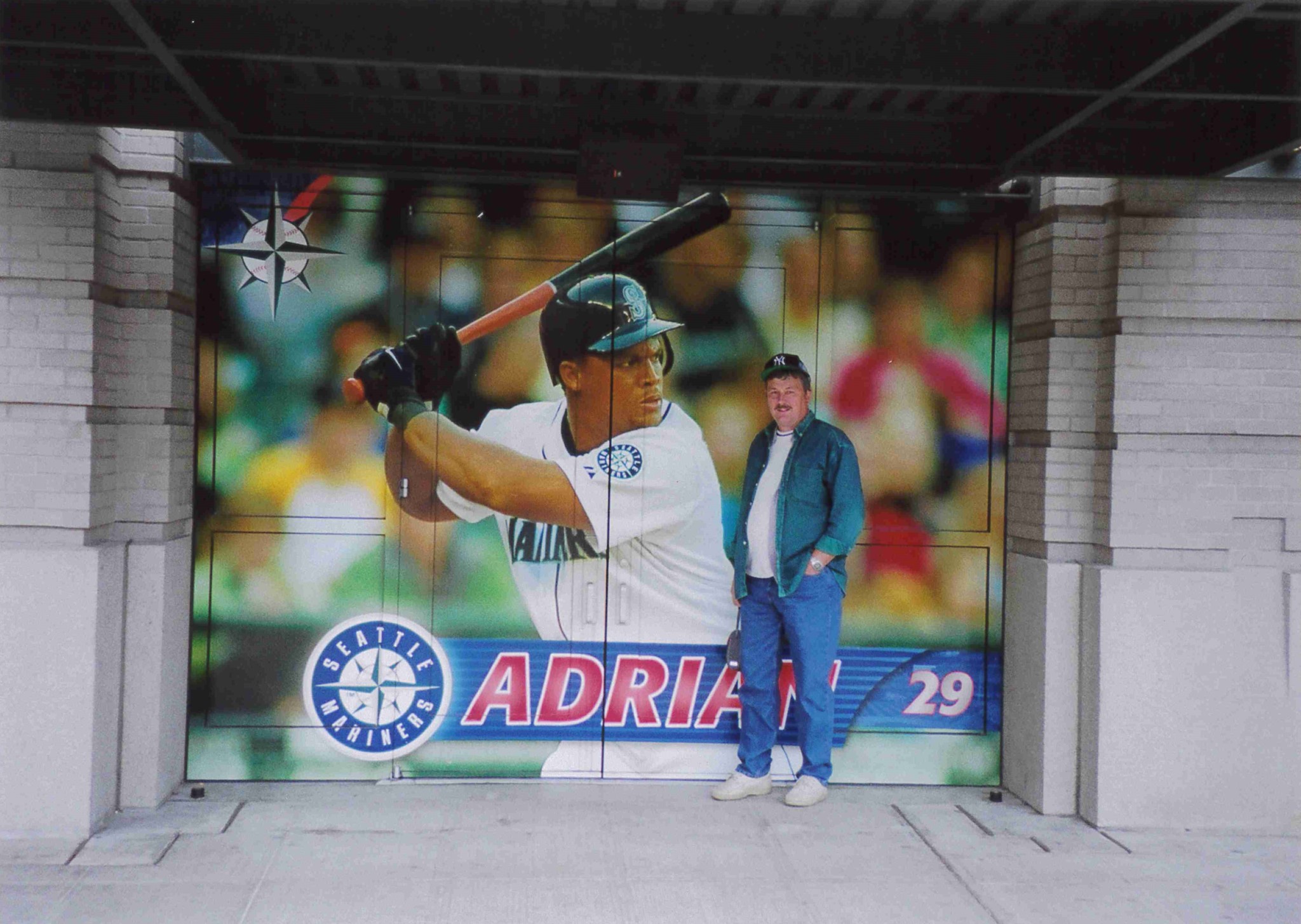 A man standing in front of a mural of a baseball player